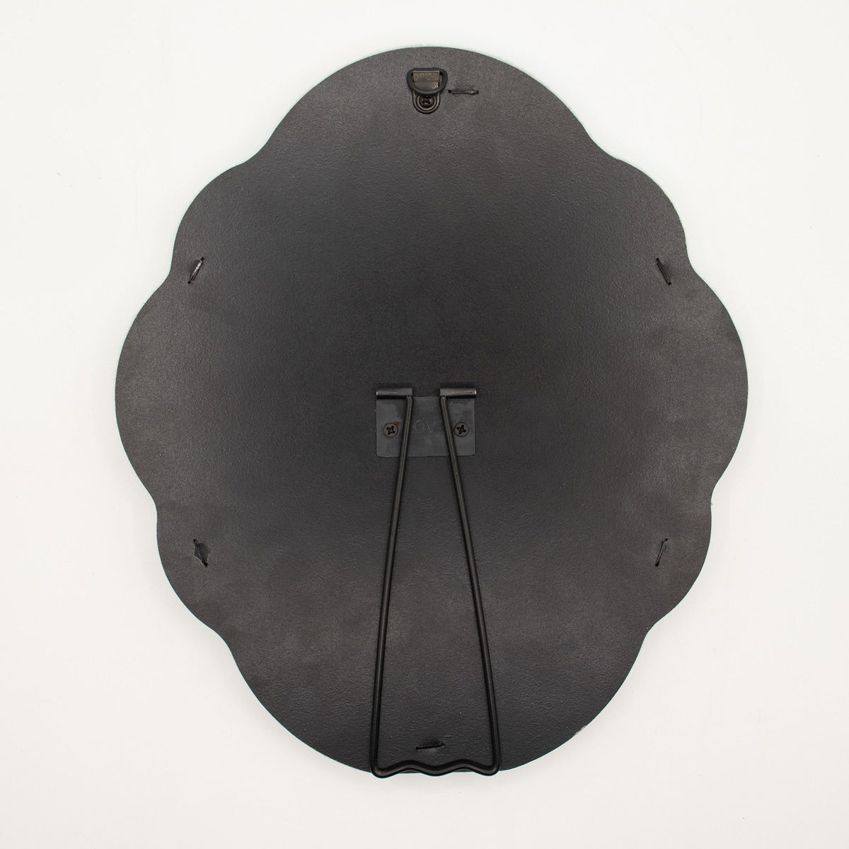 Black scalloped-edged back of a mirror showing hook and stand on a white background