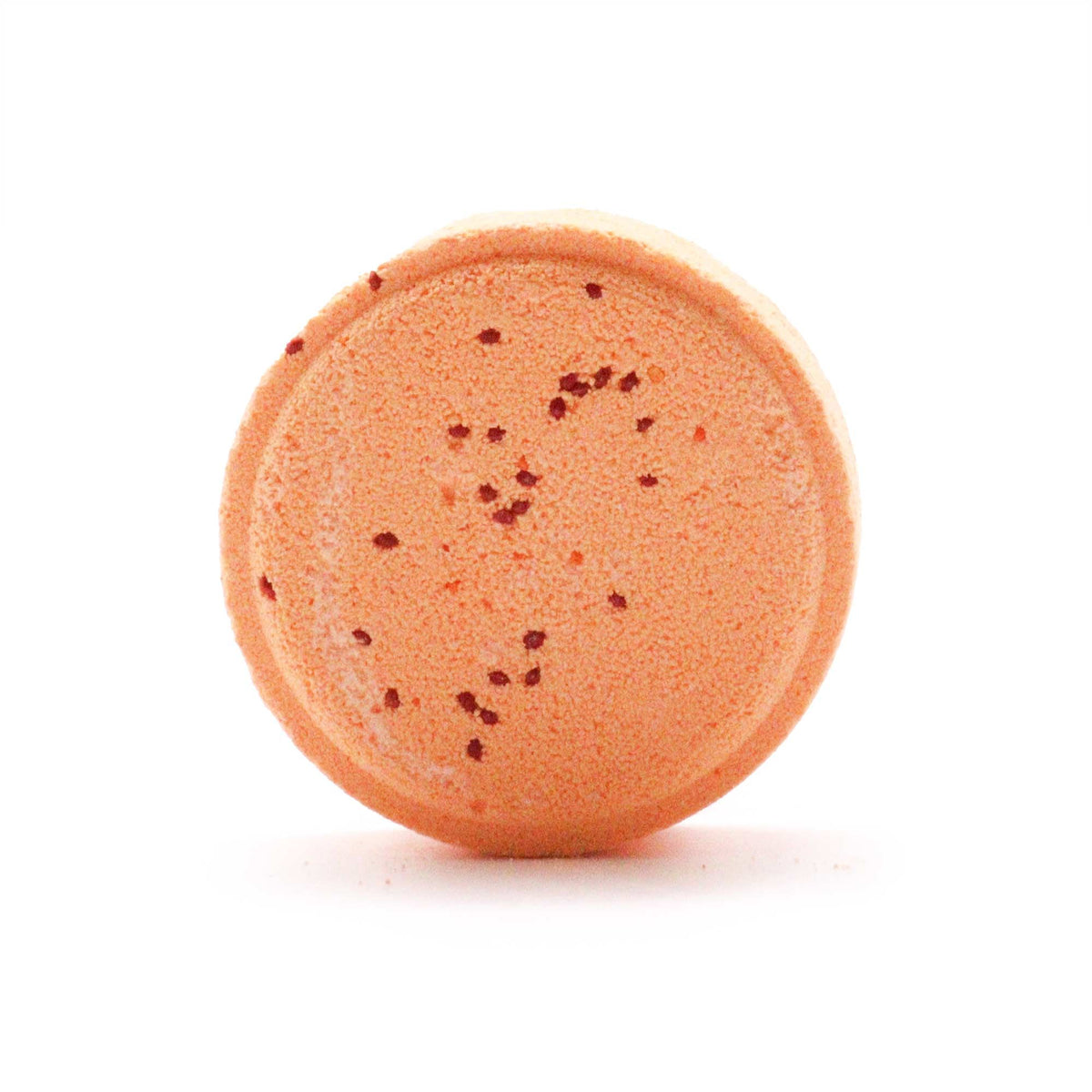 Round orange bath bomb with specks on a white background