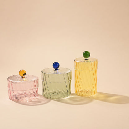 Three glass containers with colored lids on a beige background