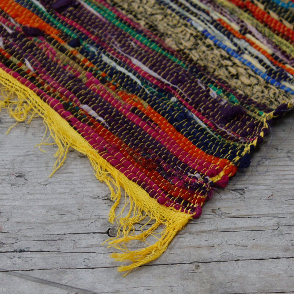 Colorful woven rug with fringes on a wooden floor