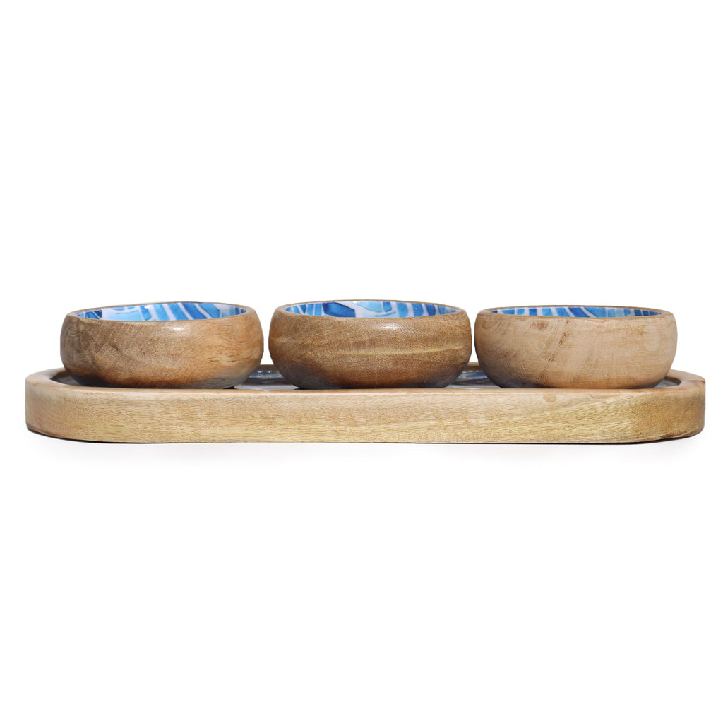 Set of three wooden bowls with blue interior on a wooden tray against a white background