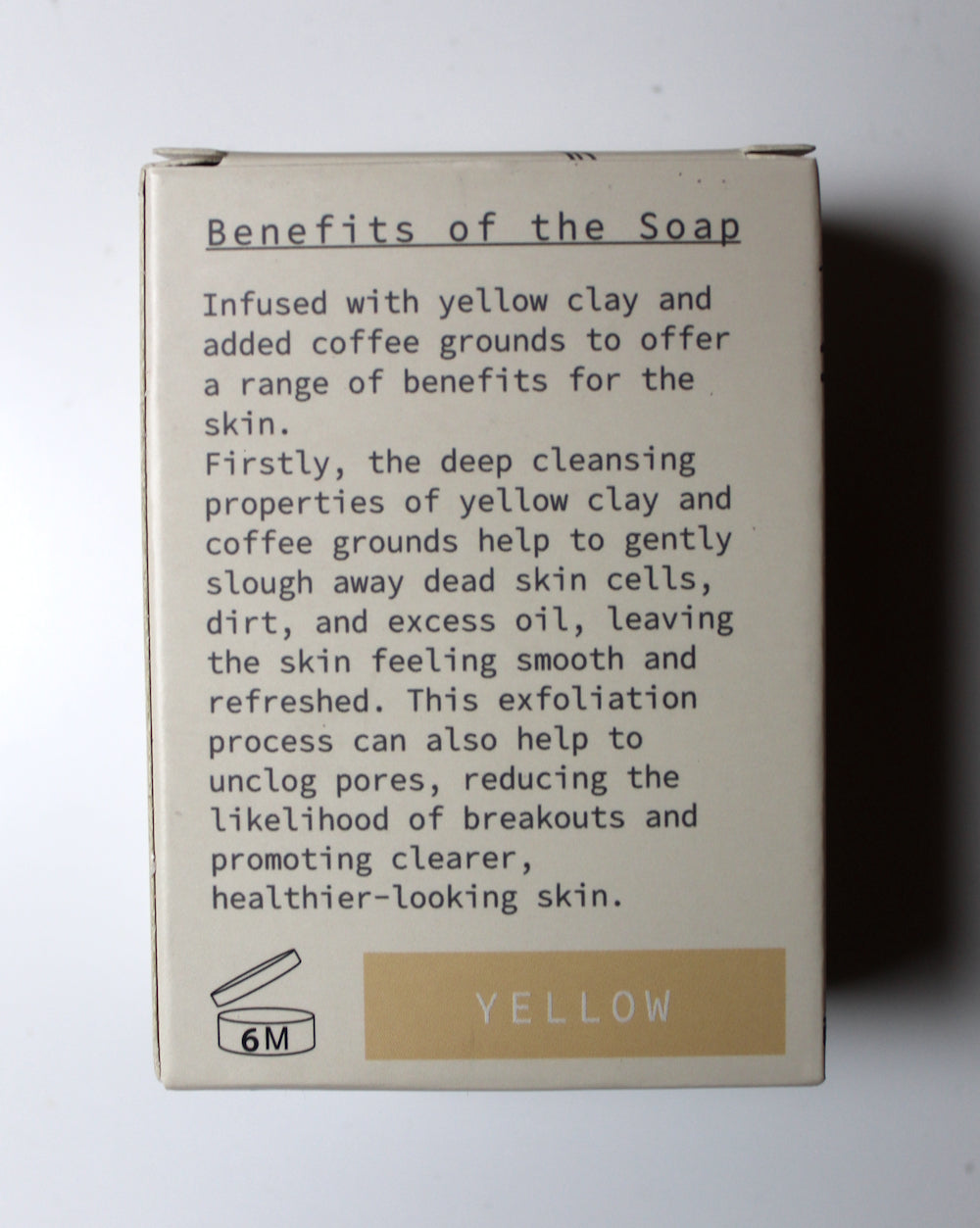 The back of a beige soap box showing product details, including a text section titled 'Benefits of the Soap' and a yellow label at the bottom indicating 'YELLOW' and '6M'.