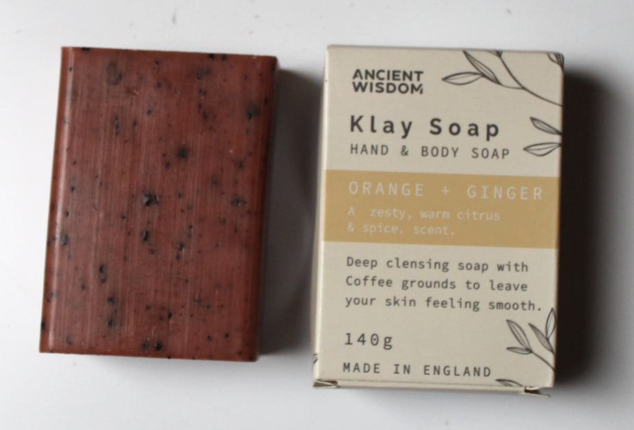 Red soap bar with black specks next to its box on a white background