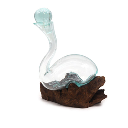 Glass decanter shaped like a swan or a dinosaur on a wooden base with a white background