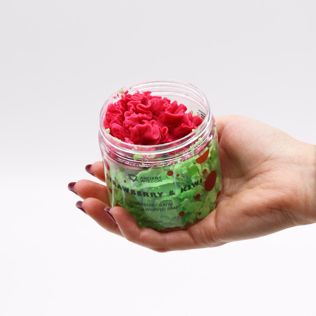 Hand holding a container of pink and green Strawberry Kiwi Whipped Soap 