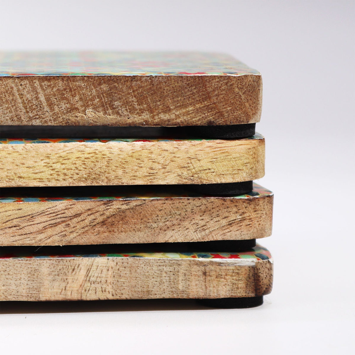 Stack of handcrafted wooden coasters with colorful patterns on a white background