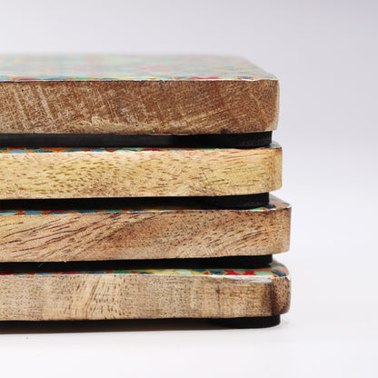 Stack of handcrafted wooden coasters with colorful patterns on a white background