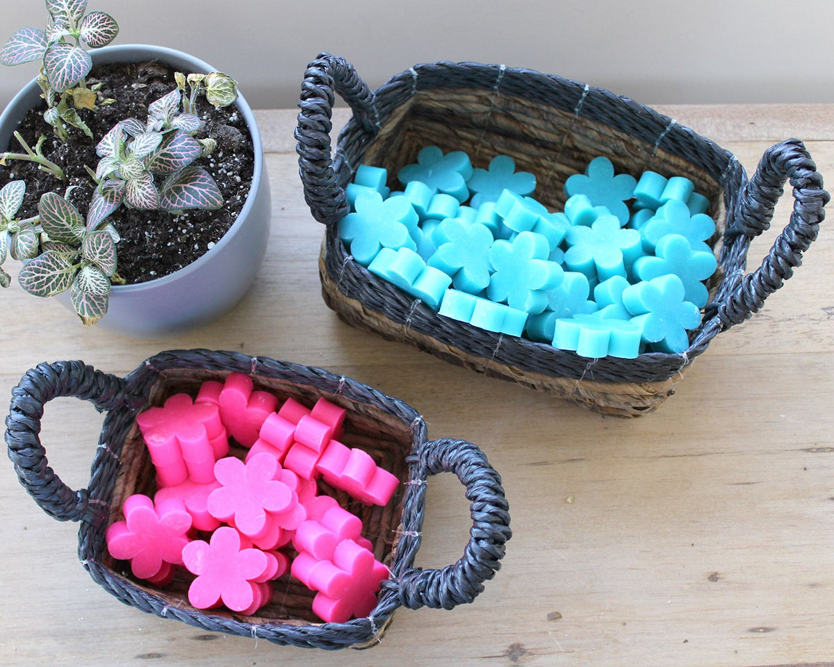 Two woven baskets filled with pink and blue flower-shaped objects on a wooden surface.