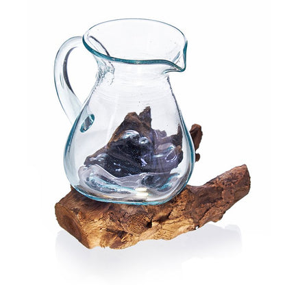 Molten Clear glass pitcher placed on a wooden log against a white background
