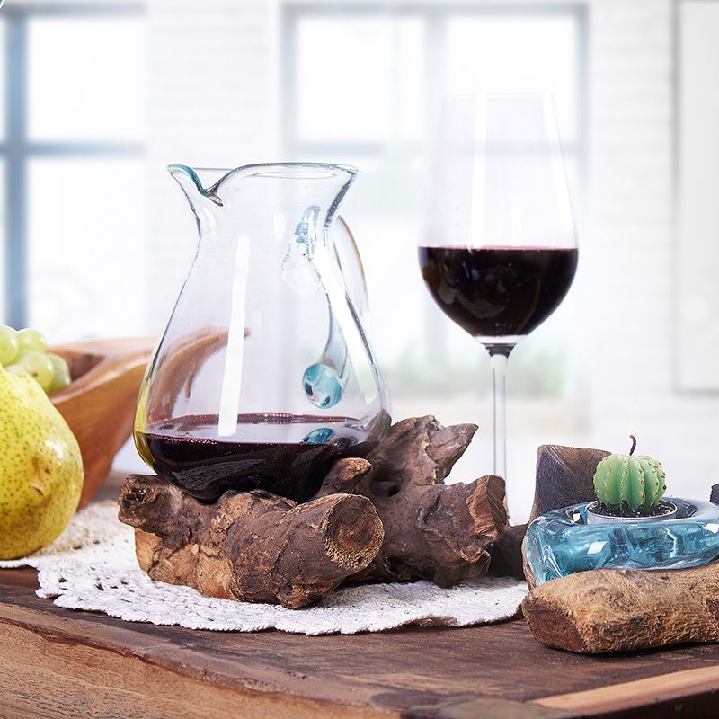 Glass carafe and wine glass with red wine on a wooden table with decorative elements.