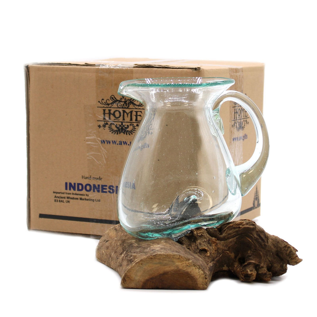 Clear glass pitcher on a wooden stand with a cardboard box labeled 'HOME' in the background.