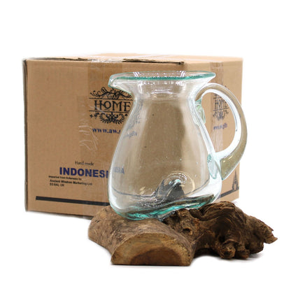 Clear glass pitcher on a wooden stand with a cardboard box labeled 'HOME' in the background.