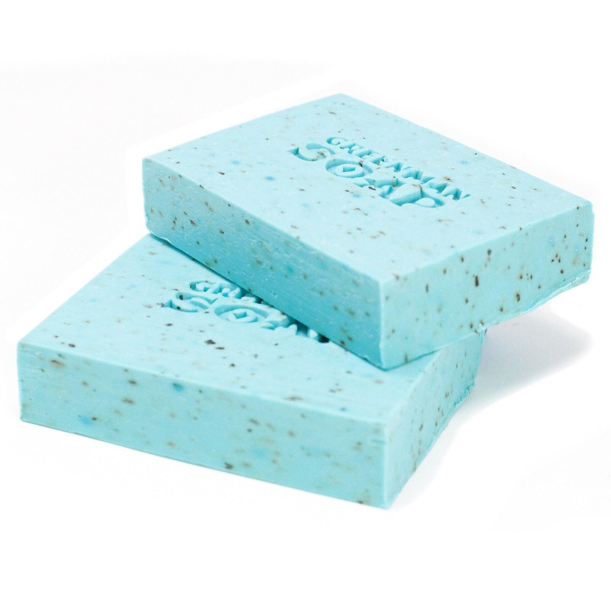 Two blocks of light blue soap with specks on a white background