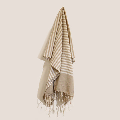 Sand and white striped towel with fringes on a beige background
