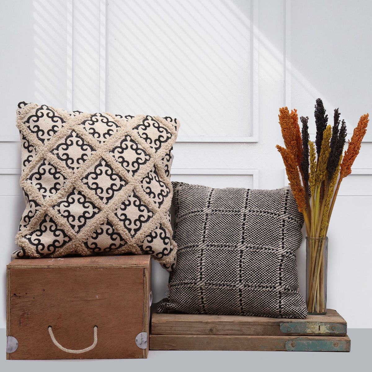 Decorative pillows and a wooden box on a white surface with a white wall background