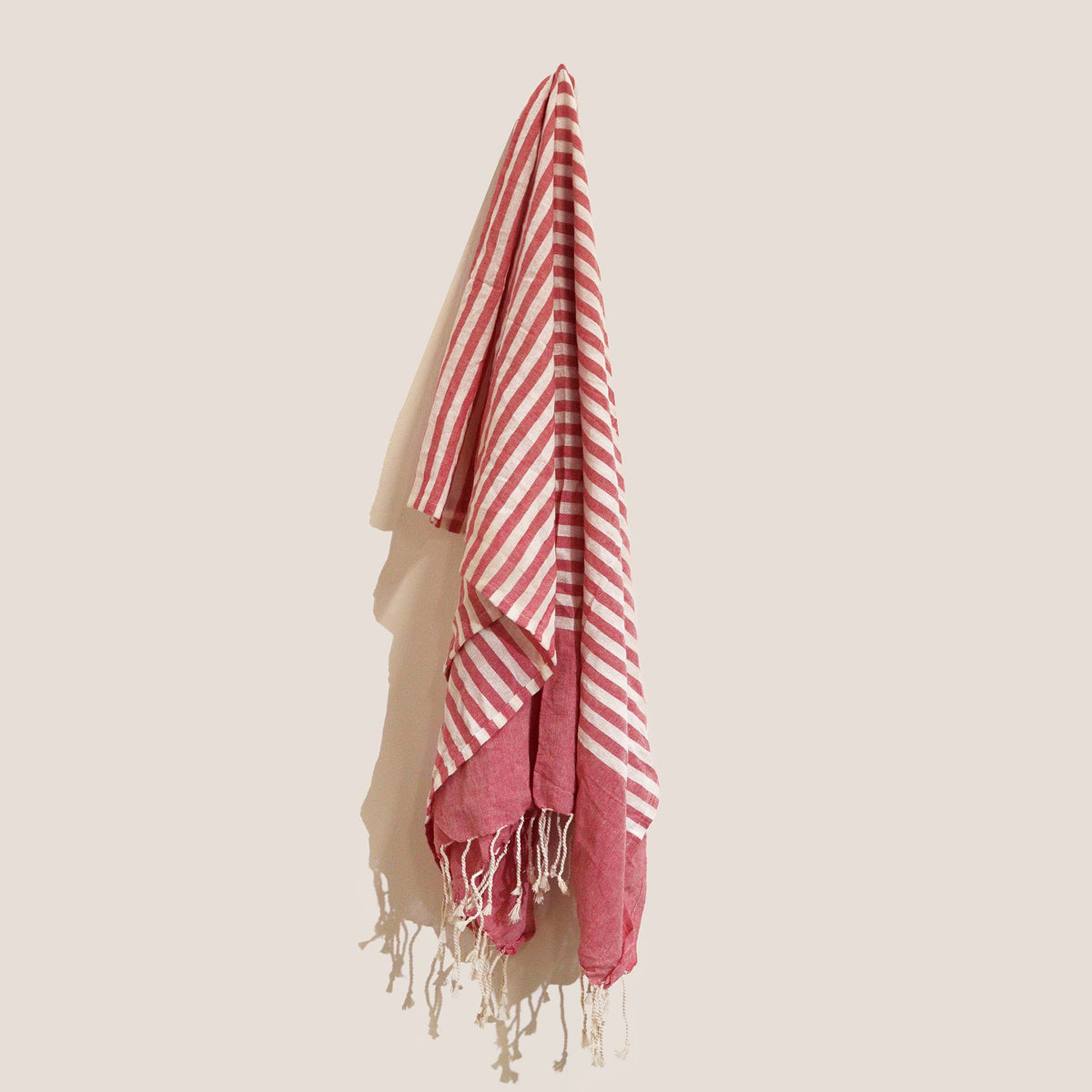 Hot Pink  and white striped towel with fringes on a beige background