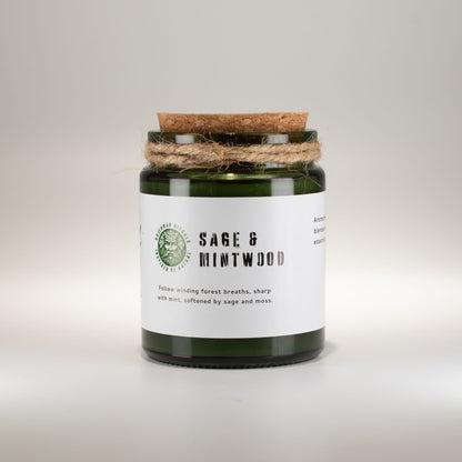 Scented candle jar labeled 'Sage & Mintwood' on a light background