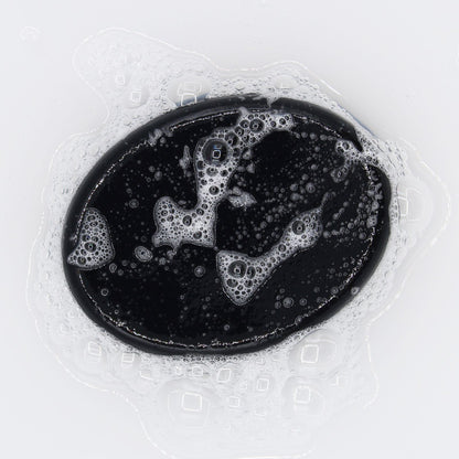 Black oval  Eucalyptus Cedarwood Charcoal Soap bar with bubbles on a white background