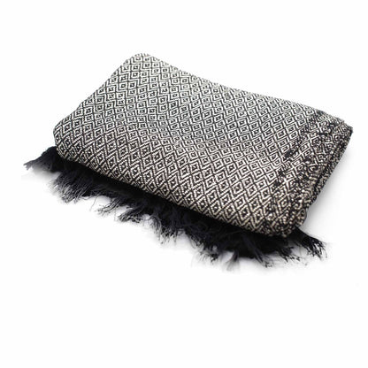 Folded blanket with geometric pattern and black fringes on a white background