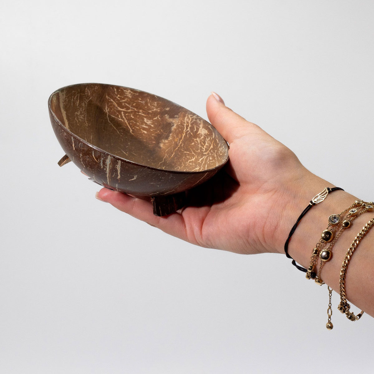 Hand holding a wooden bowl with a plain background