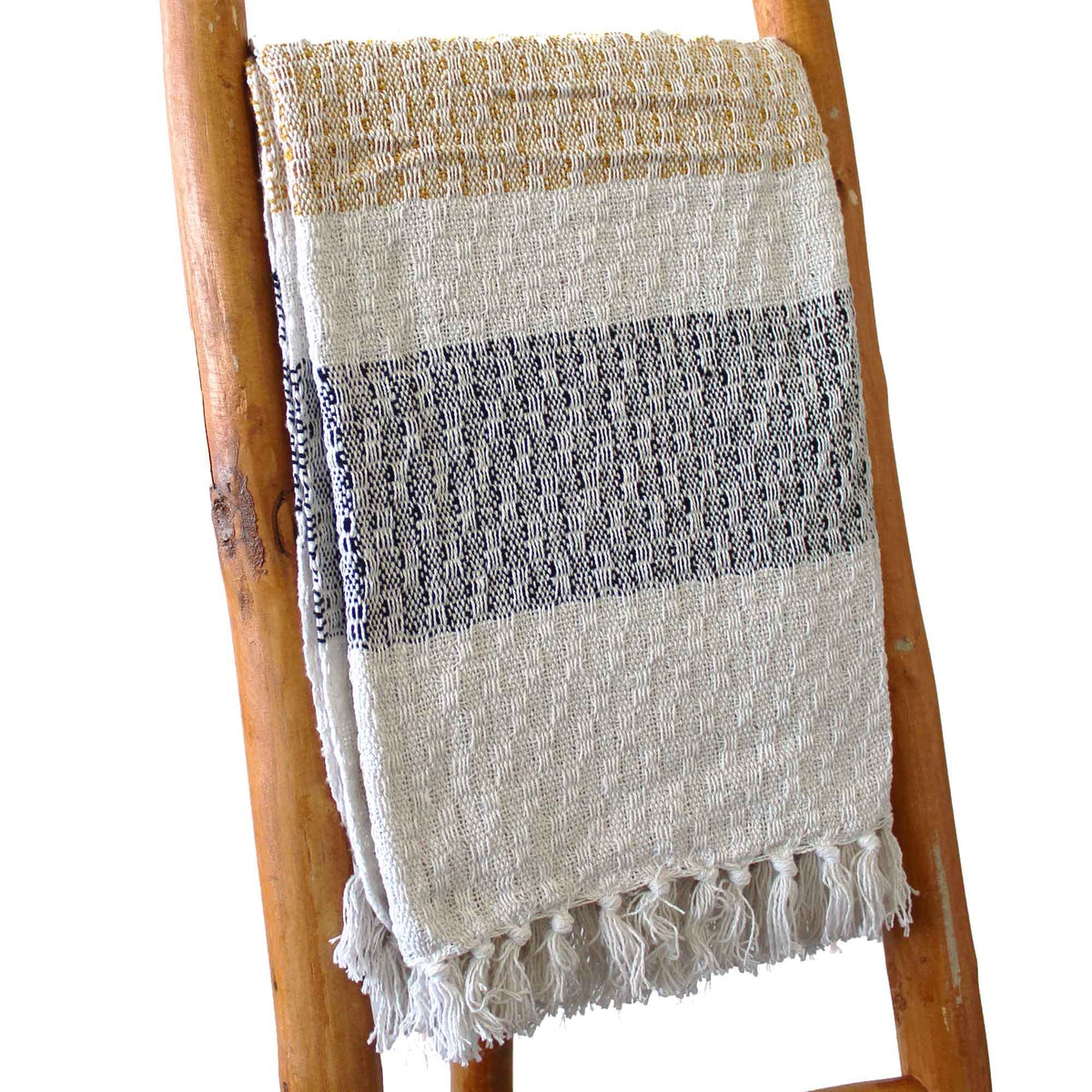 Textured blanket with striped pattern draped over a wooden ladder on a white background