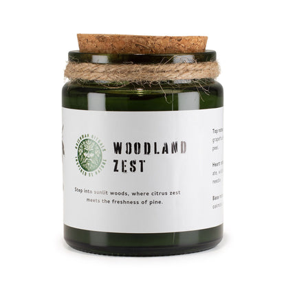 Candle jar labeled 'Woodland Zest' with a cork lid on a white background