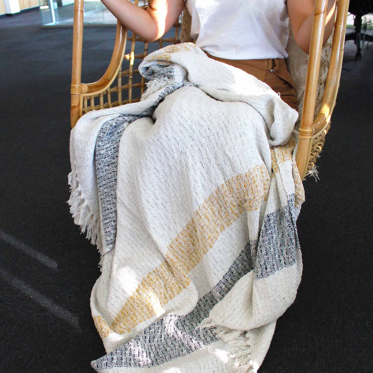 Person sitting on a chair with a textured blanket draped over them