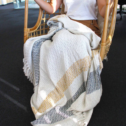 Person sitting on a chair with a textured blanket draped over them