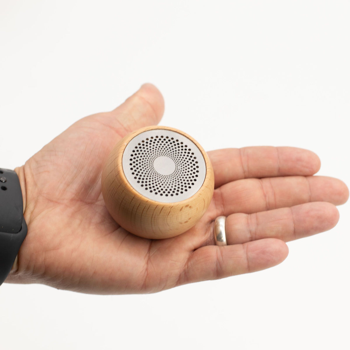 Small wooden speaker held in a hand on a white background