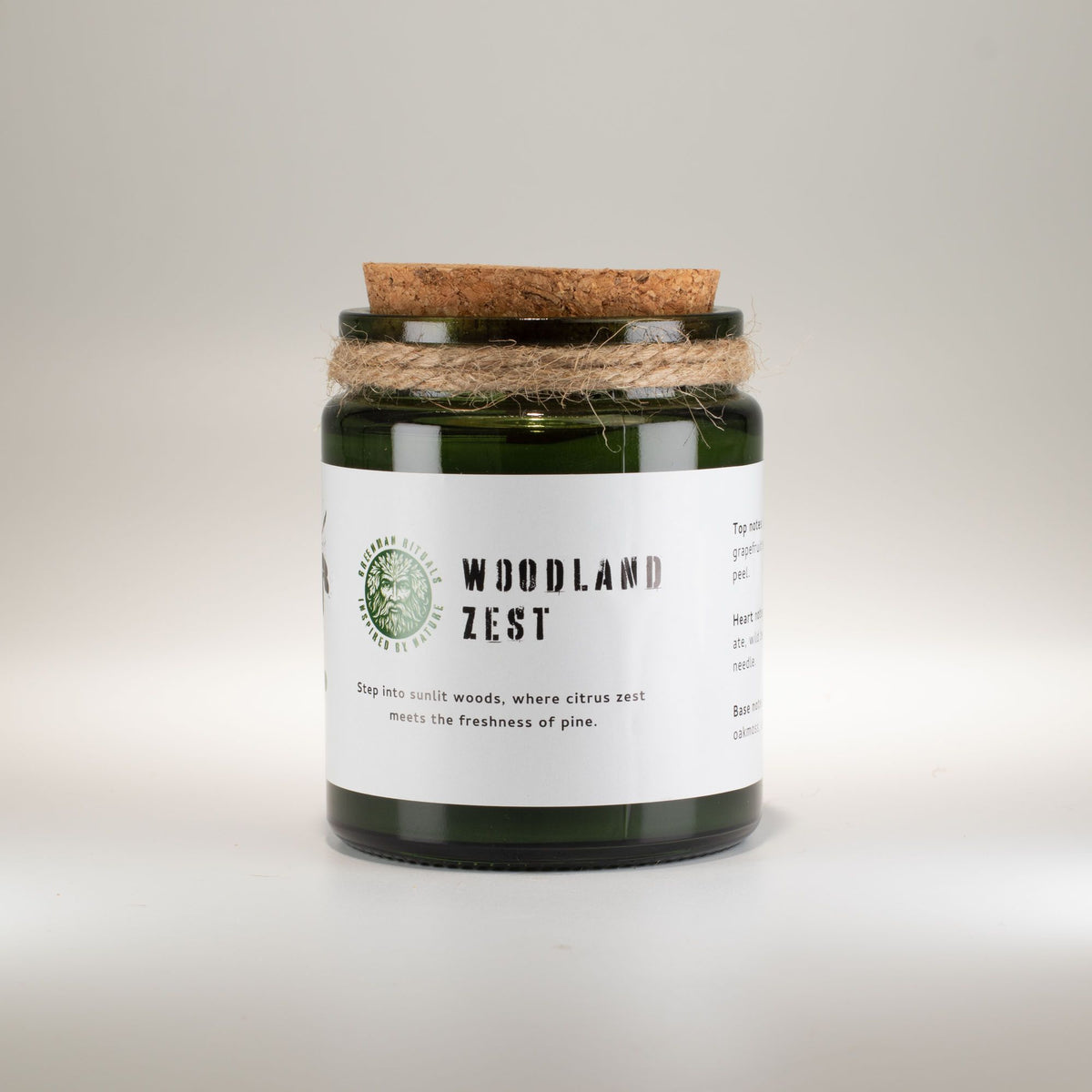 Candle jar labeled 'Woodland Zest' with a cork lid on a light gray background