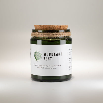 Candle jar labeled 'Woodland Zest' with a cork lid on a light gray background