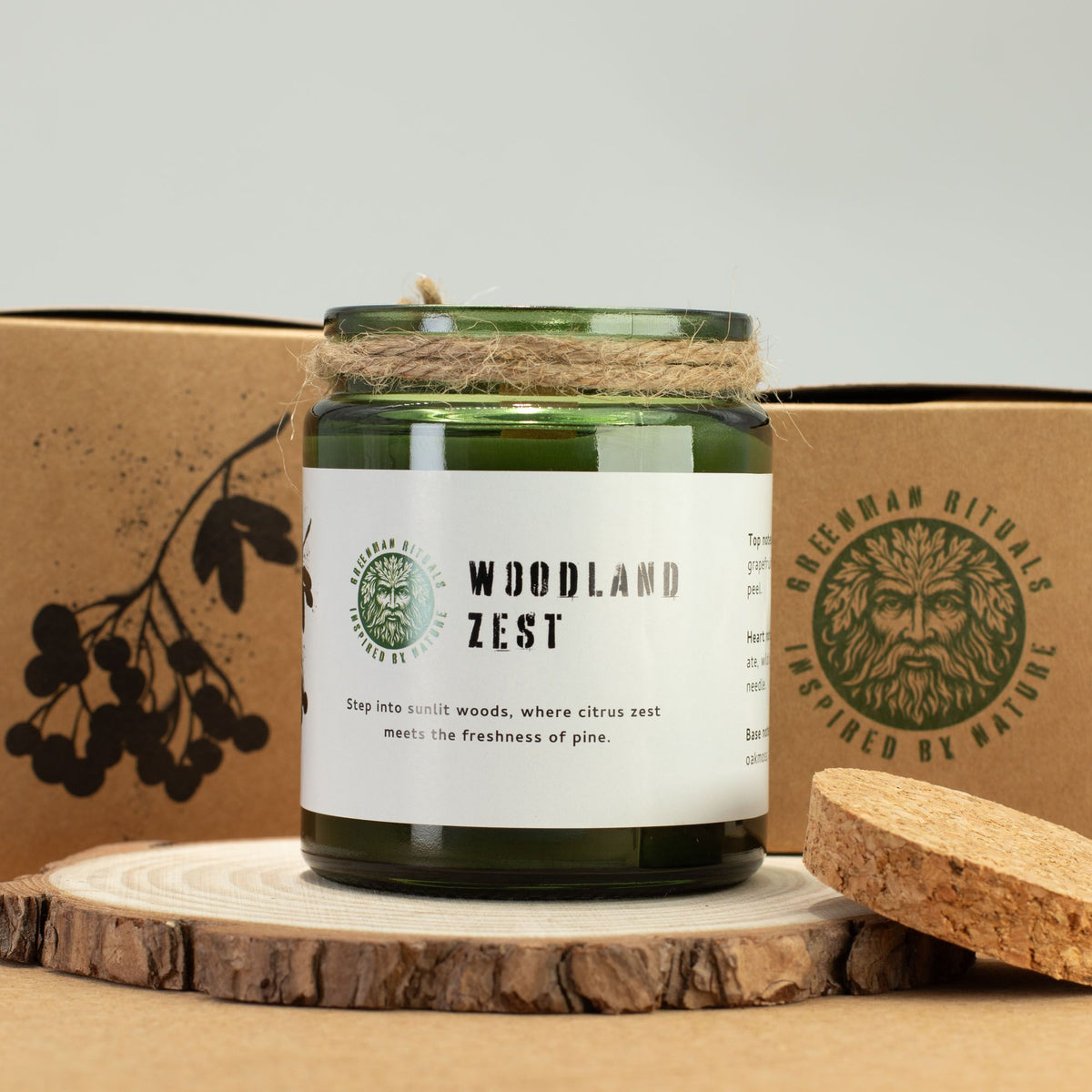 Candle labeled 'Woodland Zest' with a natural design on a wooden surface and cardboard box background.