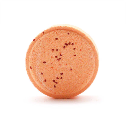 Round orange bath bomb with specks on a white background