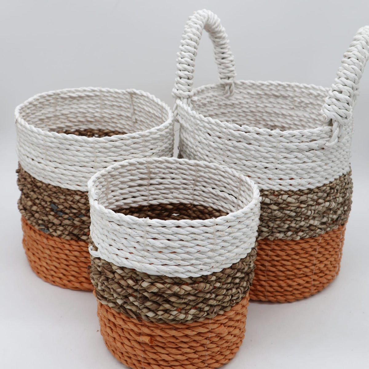 Three woven baskets with striped pattern on a white background