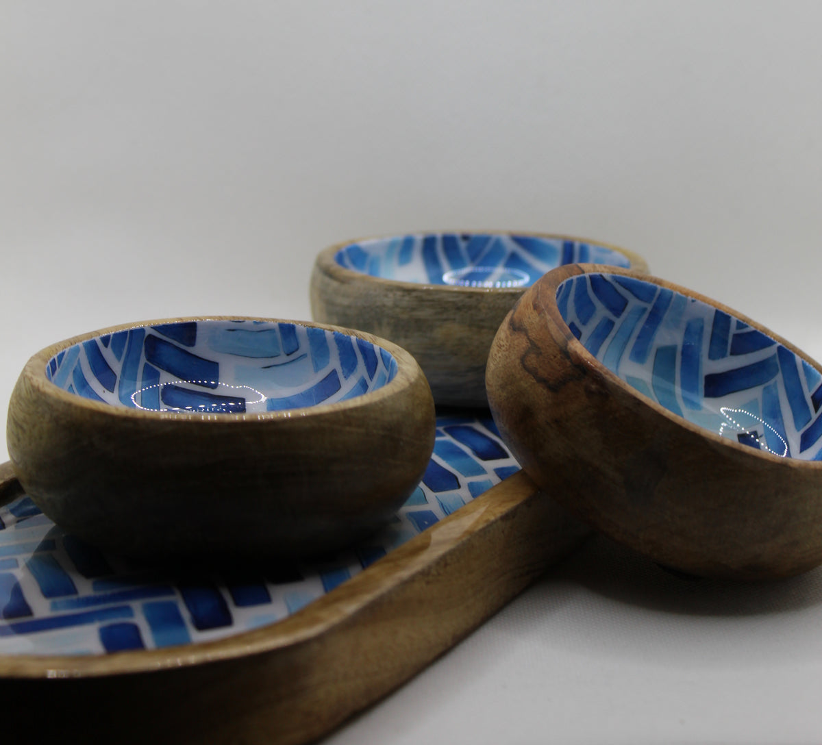 Three wooden bowls with blue and white patterns on a matching tray.