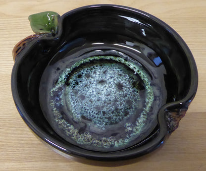 Black ceramic bowl with a green interior on a wooden surface